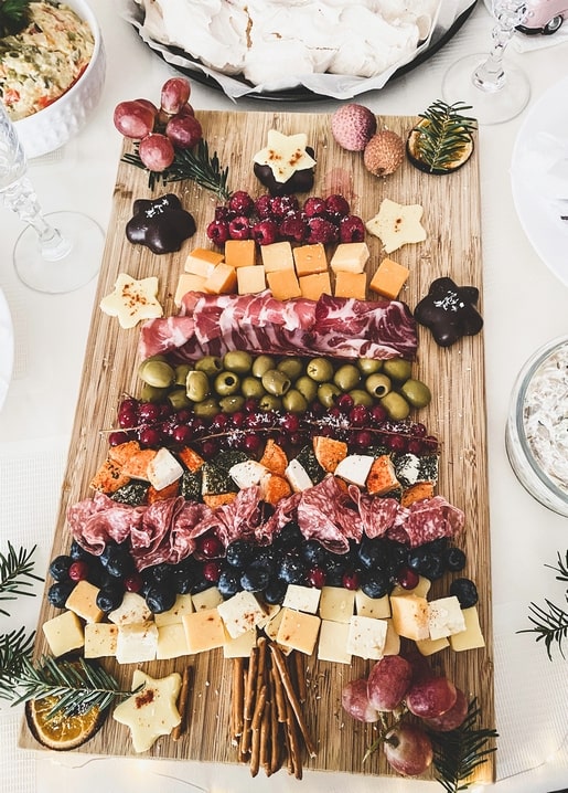 Christmas tree shaped charcuterie board with cheese, olives, and chocolate stars