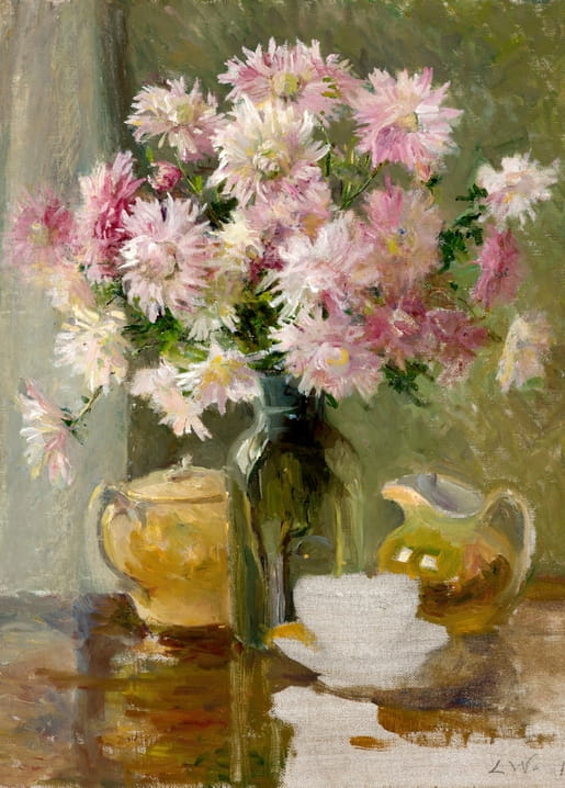Pink and white chrysanthemums in a glass jar beside a yellow teapot and creamer on a table