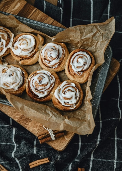 Iced cinnamon rolls on a wooden board with cinnamon sticks, postcard photo