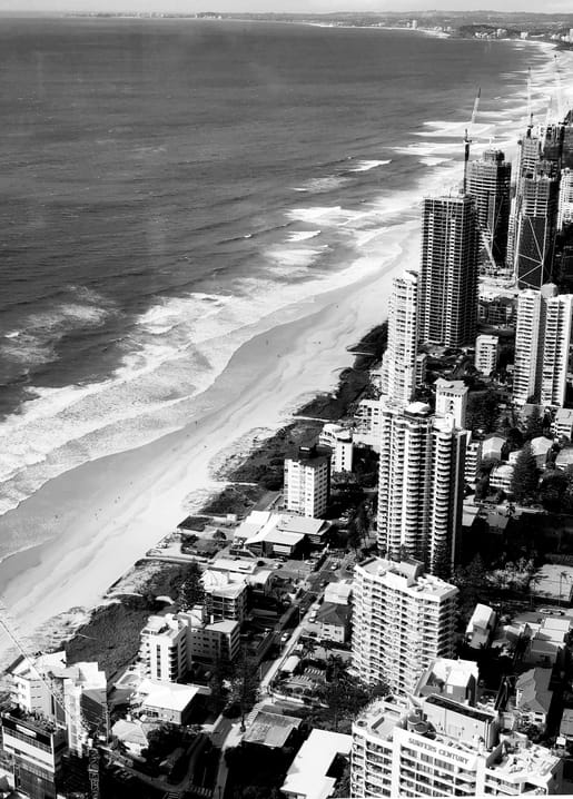 Aerial black-and-white photo of high-rise buildings along a curving beach