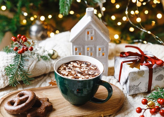 Mug of cocoa with marshmallows beside gingerbread pretzels and a wrapped gift