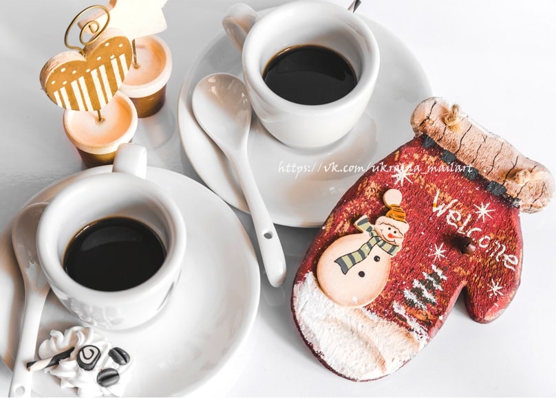 Zwei Kaffeetassen neben einem Lebkuchen-Fäustling mit 'Welcome'-Schneemann