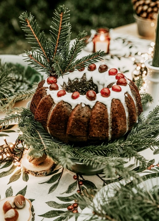 Cranberry bundt cake with pine branches and candle on a festive table