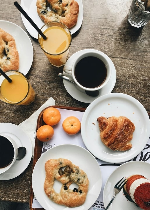 Flat lay of croissant, coffee, orange juice and tangerines on a wooden table