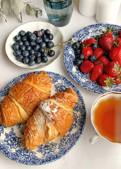 Flat lay of croissants, blueberries, strawberries and tea on blue-and-white china