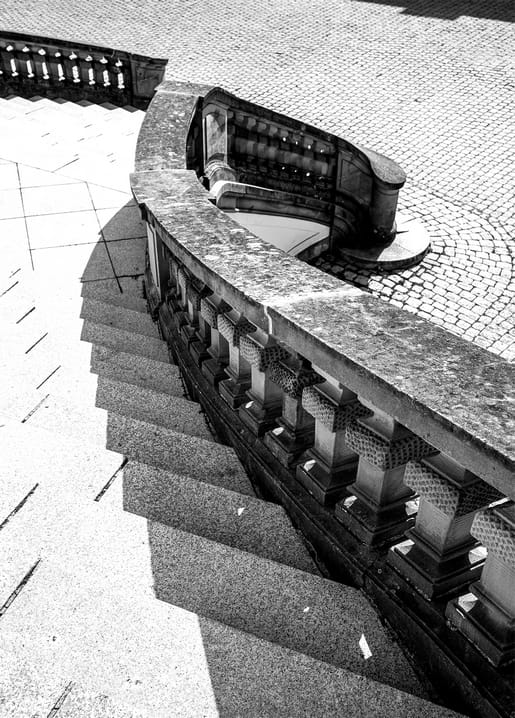 Blick von oben auf eine Steintreppe mit Balustrade und langen Schatten