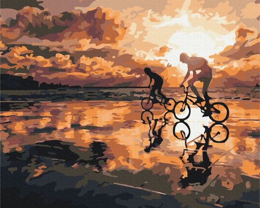 Erwachsener und Kind fahren bei Sonnenuntergang am nassen Strand Rad