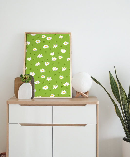 Daisy pattern poster leaning against a dresser beside a moon lamp and snake plant