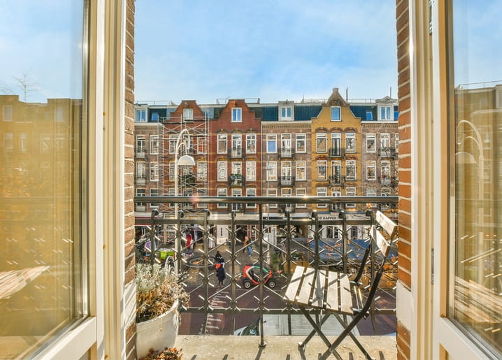 Blick auf niederländische Giebelhäuser und einen Balkon durch ein offenes Fenster