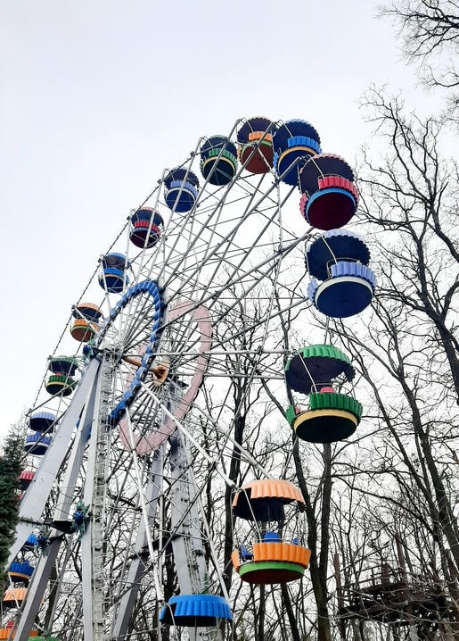 Colorful Ferris wheel rising above bare winter branches in Holosiiv Park, Kyiv