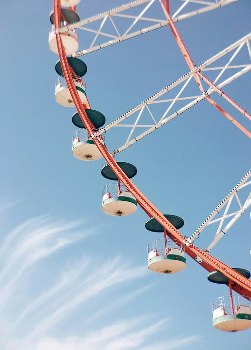 Red and white Ferris wheel with teal gondolas against a clear summer sky