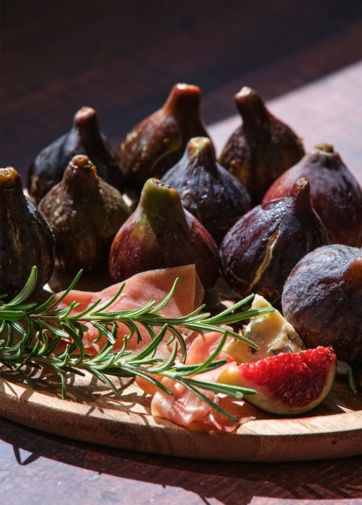 Reife Feigen mit Prosciutto, Blauschimmelkäse und Rosmarin auf einem Holzbrett