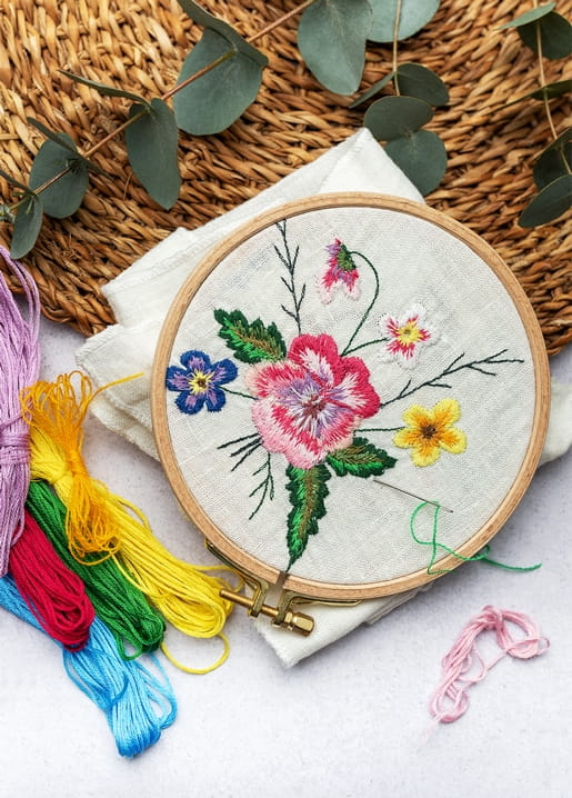 Finished floral embroidery hoop with thread skeins and eucalyptus leaves