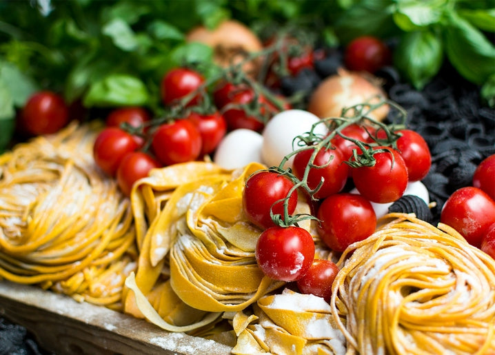 Fresh pasta nests with cherry tomatoes on the vine, basil, eggs and onions