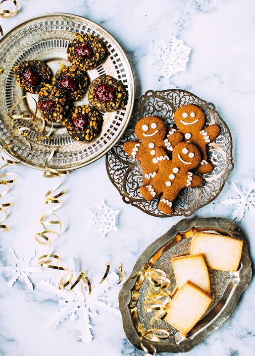 Gingerbread men, jam thumbprint cookies, and shortbread on vintage silver trays with gold ribbon