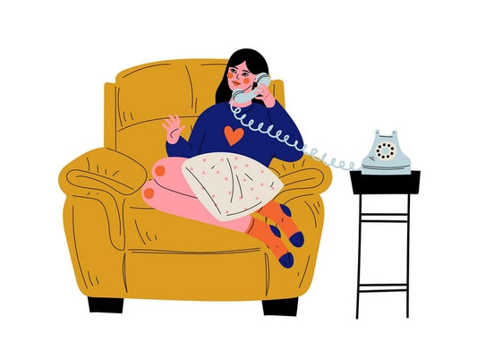 Girl in a heart sweater talking on a vintage rotary phone in a yellow armchair