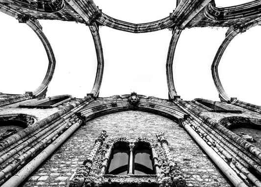 Black-and-white view looking up at Gothic ribbed vaulting and a carved stone window