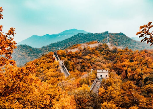 Die Chinesische Mauer schlängelt sich durch nebelige, herbstlich gefärbte Berge.