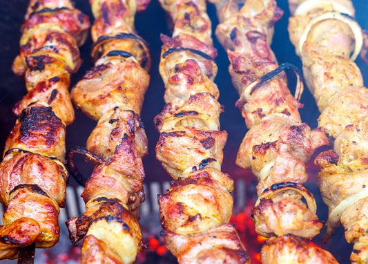 Schaschlik-Spieße mit Zwiebelringen grillen über glühender Kohle