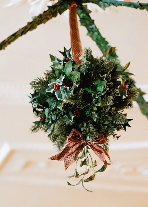 Hanging bundle of holly, ivy and pine tied with a rust-red ribbon