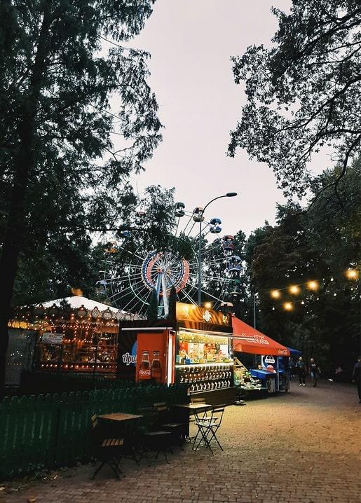 Lit Ferris wheel and glowing kiosks at dusk in Holosiiv Park, Kyiv