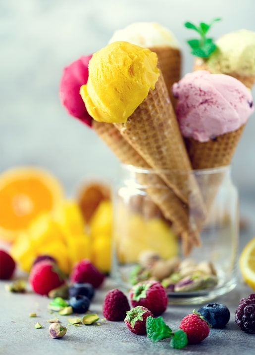 Waffeltüten mit Mango-, Himbeer- und Pistazieneis stehen als Bouquet in einem Glas