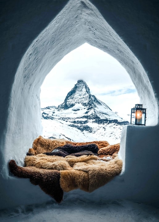 Igloo window with sheepskin throws framing a view of the snow-capped Matterhorn