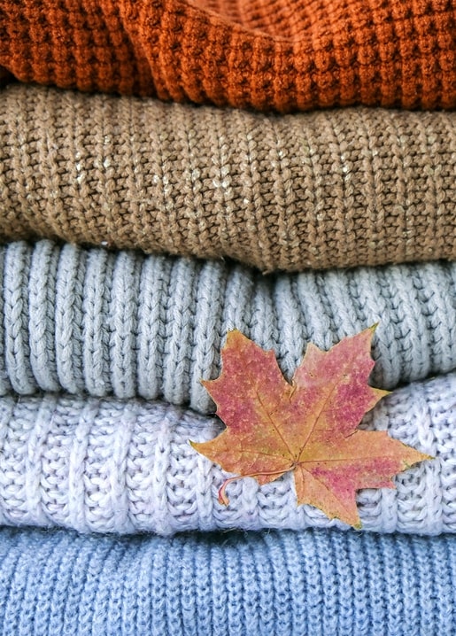 Gestapelte Strickpullover mit einem Ahornblatt obenauf