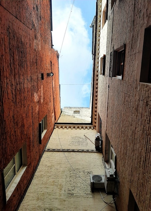 Narrow brick courtyard passage between Kyiv tenement buildings with a strip of sky above