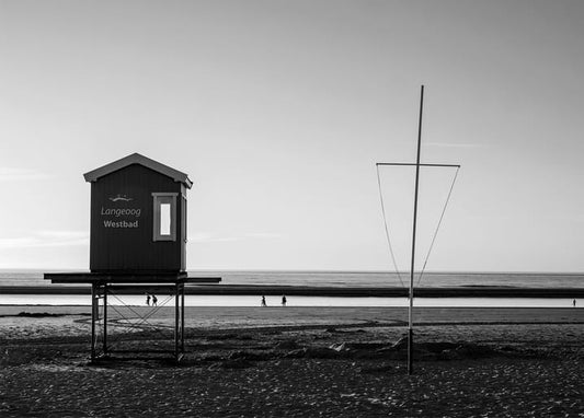 Black-and-white photo of the Langeoog Westbad beach hut on stilts with a wire sculpture