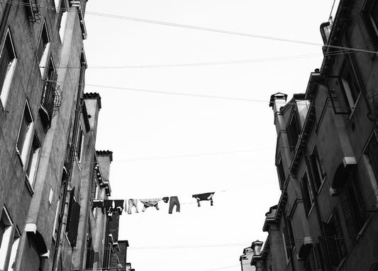 Black-and-white photo of laundry hanging on a line between narrow old buildings