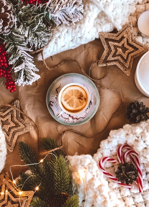 Cup of lemon tea among gold star ornaments and candy canes