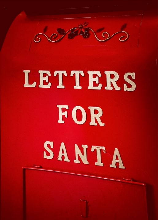 Close-up of a red mailbox embossed with ‘Letters for Santa’ and a holly decoration