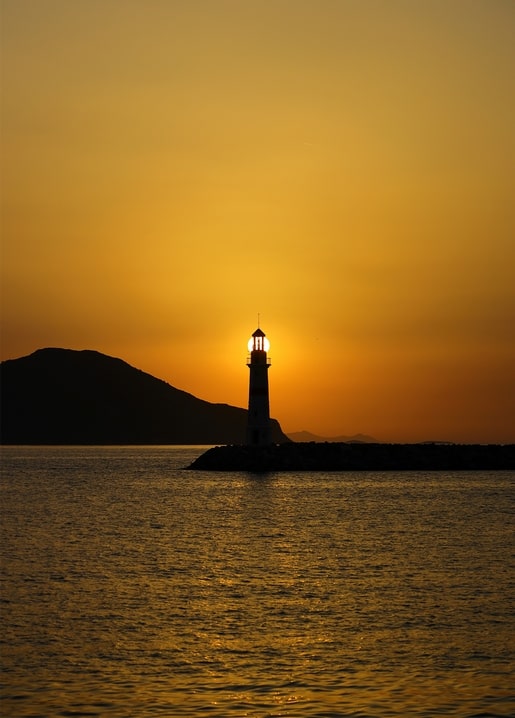 Silhouette eines Leuchtturms im goldenen Sonnenuntergang über dem Meer