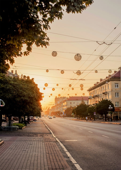 Lutsk street at sunset with round string lights strung above an empty road