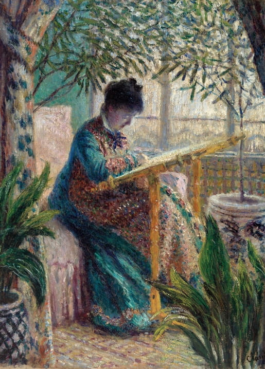 Woman in a teal jacket embroidering on a tapestry frame on a sunlit veranda with potted plants