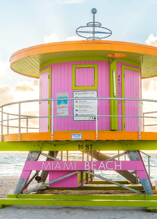 Pink-grüner Rettungsturm mit Miami-Beach-Schriftzug unter blauem Himmel