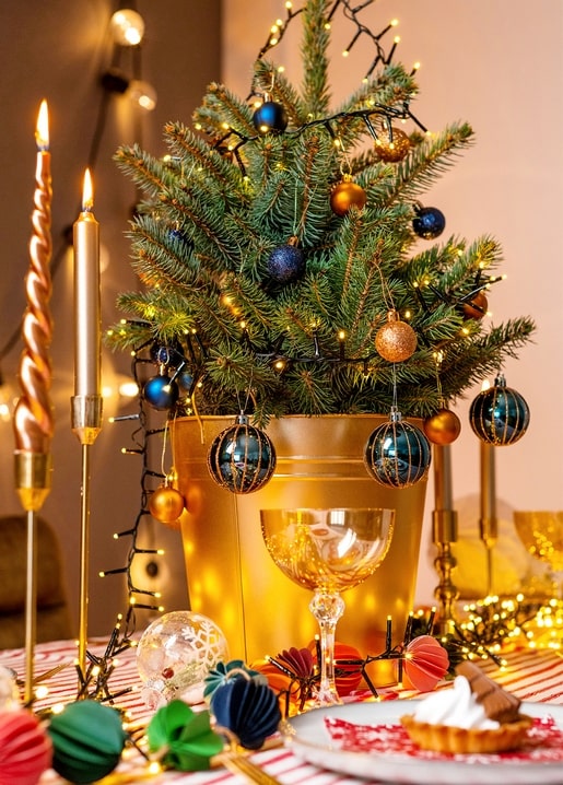 Postcard of a mini Christmas tree in a gold planter with candles and a slice of pie