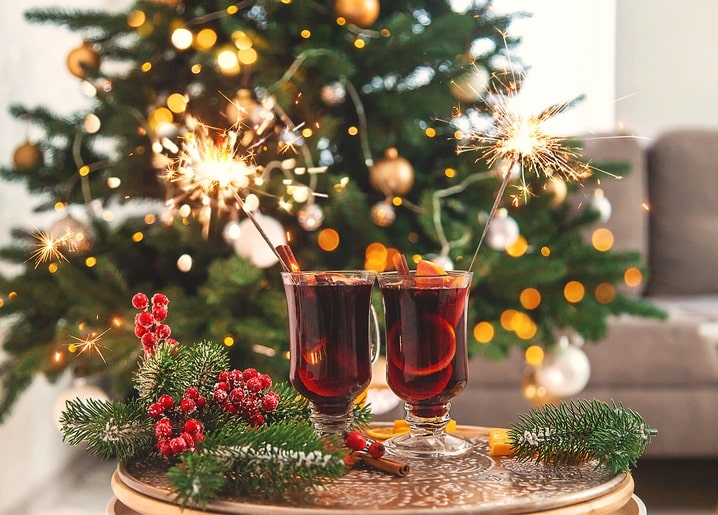 Two glasses of mulled wine with sparklers in front of a Christmas tree