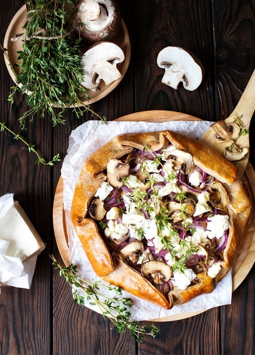 Pilz-Ziegenkäse-Galette mit Thymian auf einem rustikalen Holzbrett