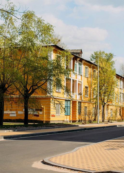 Ochre-yellow building on a quiet Kyiv street corner framed by fresh spring trees