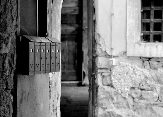 Row of old metal mailboxes beside a stone archway, black-and-white photograph