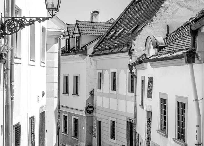 Schwarz-weiße Straße einer europäischen Altstadt mit Ziegeldächern und schmiedeeiserner Laterne