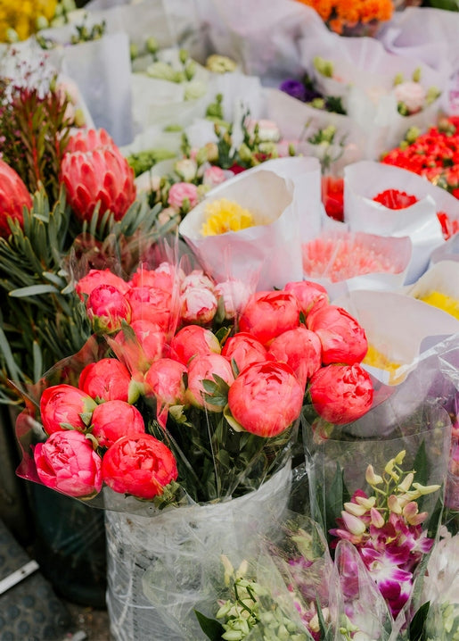 Bunches of pink peonies wrapped in paper at a flower market stall