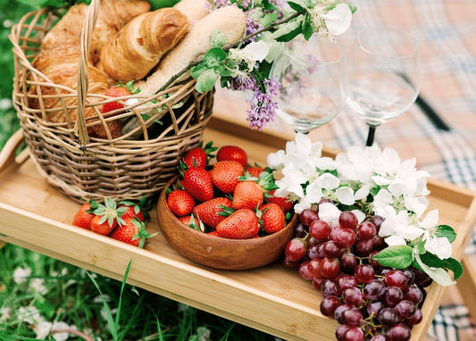 Wicker picnic basket with croissants, bowl of strawberries and grapes