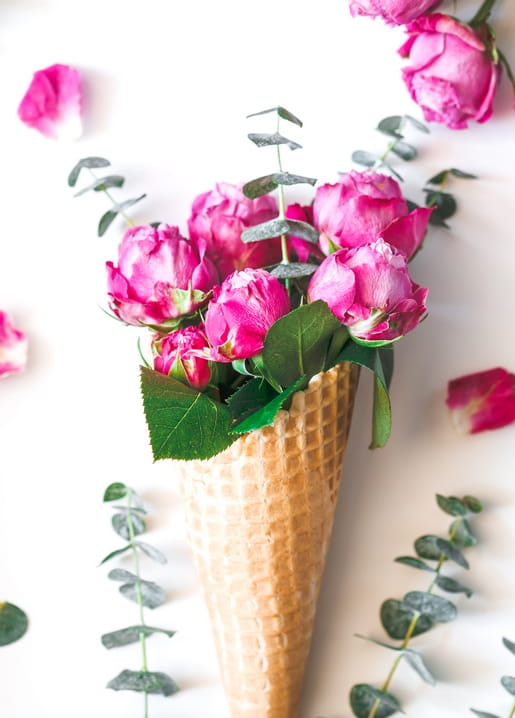 Rosa Pfingstrosen und Eukalyptus in einer Waffeltüte wie eine Kugel Eis