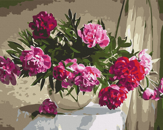 Bouquet of pink and burgundy peonies in a white vase on a table