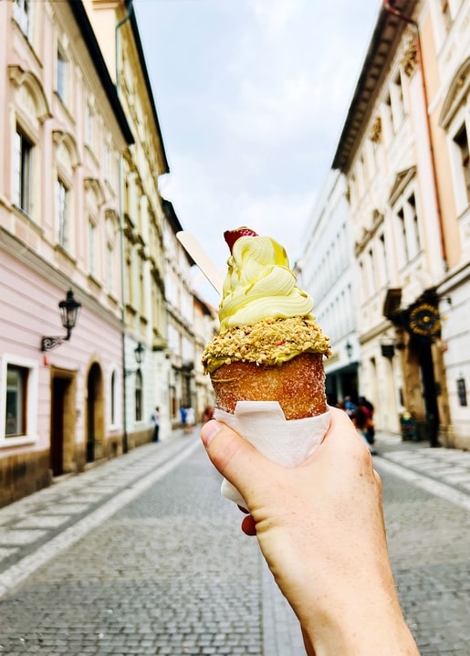 Pistazien-Eiswaffel mit Erdbeere über einer Kopfsteinpflastergasse