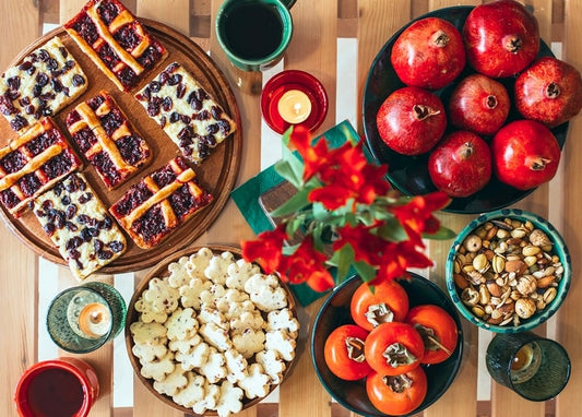 Herbsttisch mit Granatäpfeln, Kaki, Beerengebäck, Nüssen, Tulpen und Kerzen