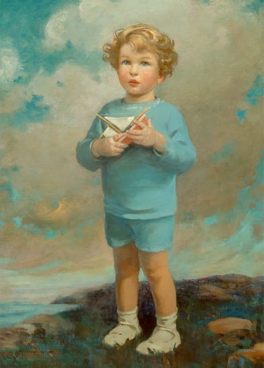 Curly-haired boy in blue clothing holding a paper boat on a rocky coastal cliff